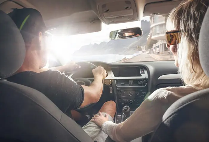 Couple driving a rental car along the Italian coast, showing why it’s worth renting a car in Italy for flexibility and views