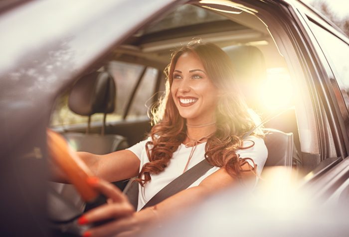 Smiling traveler driving a rental car in Italy, representing the flexibility and cost differences of renting a car by season
