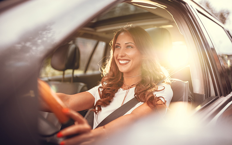Viaggiatore sorridente alla guida di un’auto a noleggio in Italia, simbolo della flessibilità e delle differenze di prezzo del noleggio auto a seconda della stagione.