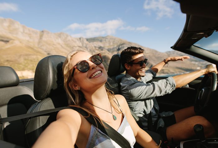 Hermosa mujer emprendiendo un viaje por carretera con su novio. Pareja joven disfrutando de un road trip en un coche descapotable.