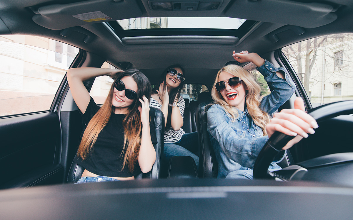Tre ragazze alla guida di una decappottabile che si divertono dopo aver acquistato l’assicurazione per il noleggio auto in Italia.