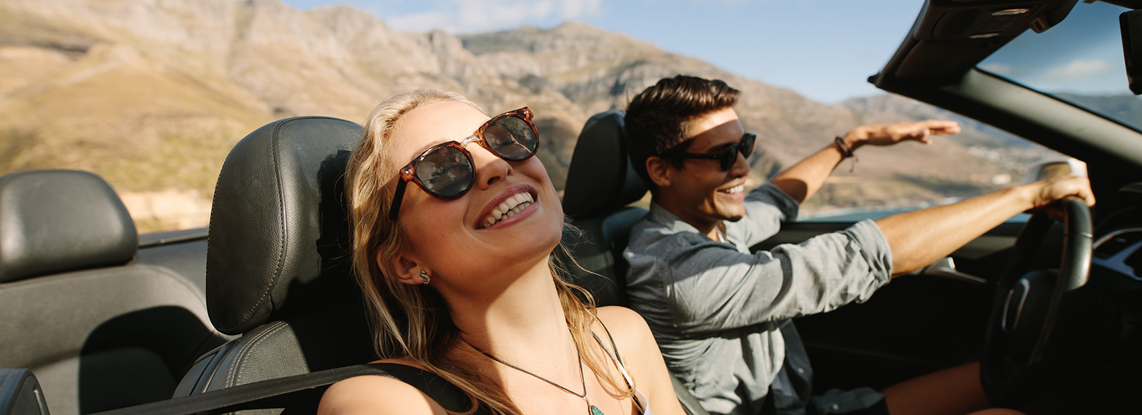 Beautiful woman going on road trip with her boyfriend. Young couple enjoying  on road trip in a convertible car.