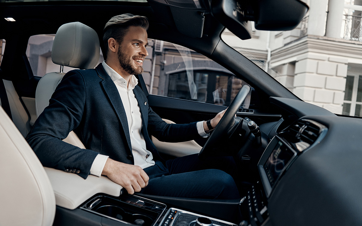 Viajero de negocios conduciendo un coche de alquiler premium por la ciudad durante una experiencia de alquiler de coches cómoda y flexible.