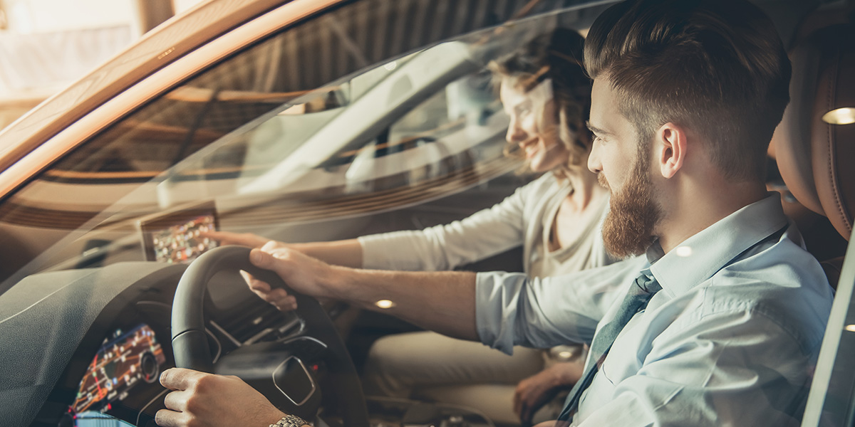 Pareja probando el tablero y el volante antes de comenzar el viaje durante un alquiler coche sin fianza.