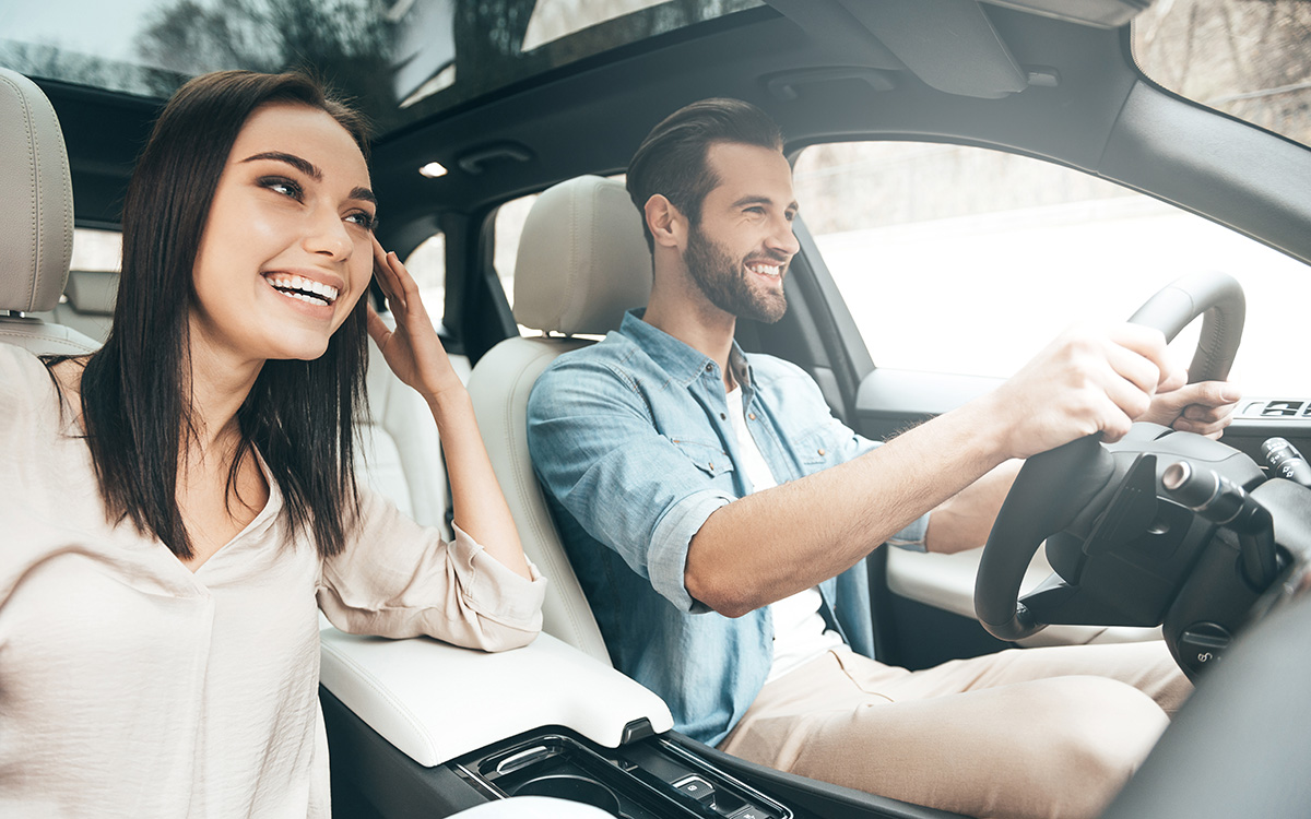 Coppia felice che si gode un viaggio su strada a bordo di una moderna auto a noleggio, rappresentando la libertà che i viaggiatori possono vivere grazie alle opzioni di noleggio auto senza carta di credito.