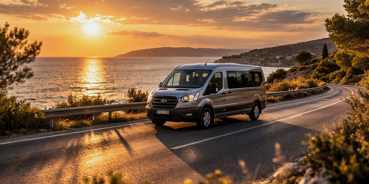 Moderner Kleinbus während der Anmietung fährt bei goldenem Abendlicht entlang einer Küstenstraße mit Blick auf das Meer und Kleinbus mieten