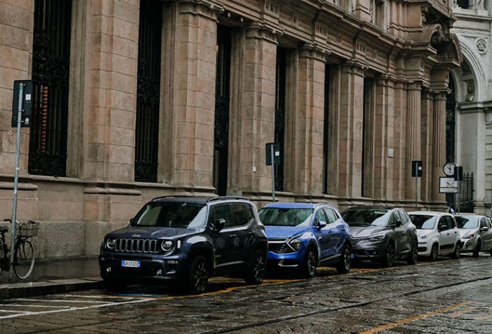 Cars parked beside a historic building on a rainy day in an Italian city