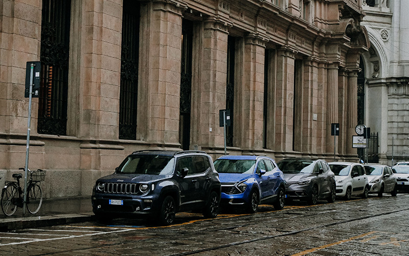 Cars parked beside a historic building on a rainy day in an Italian city