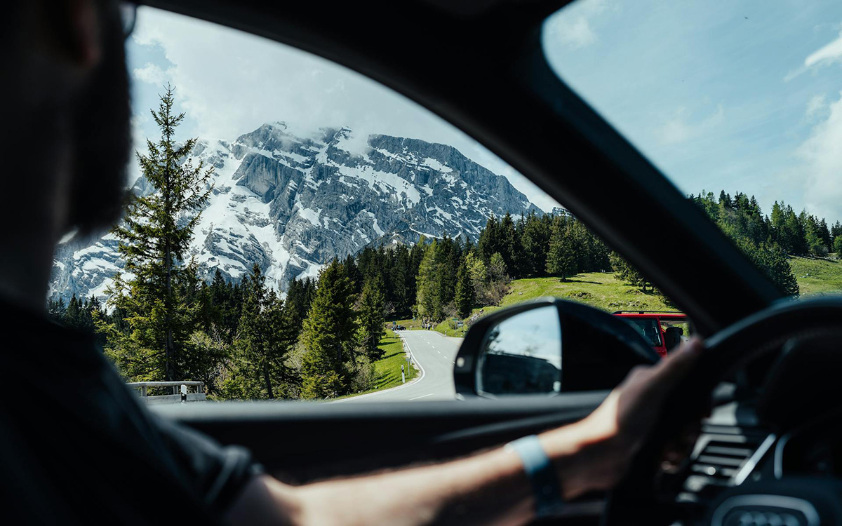 Driving in Italy on a winding mountain road with breathtaking Dolomite scenery through the windshield.