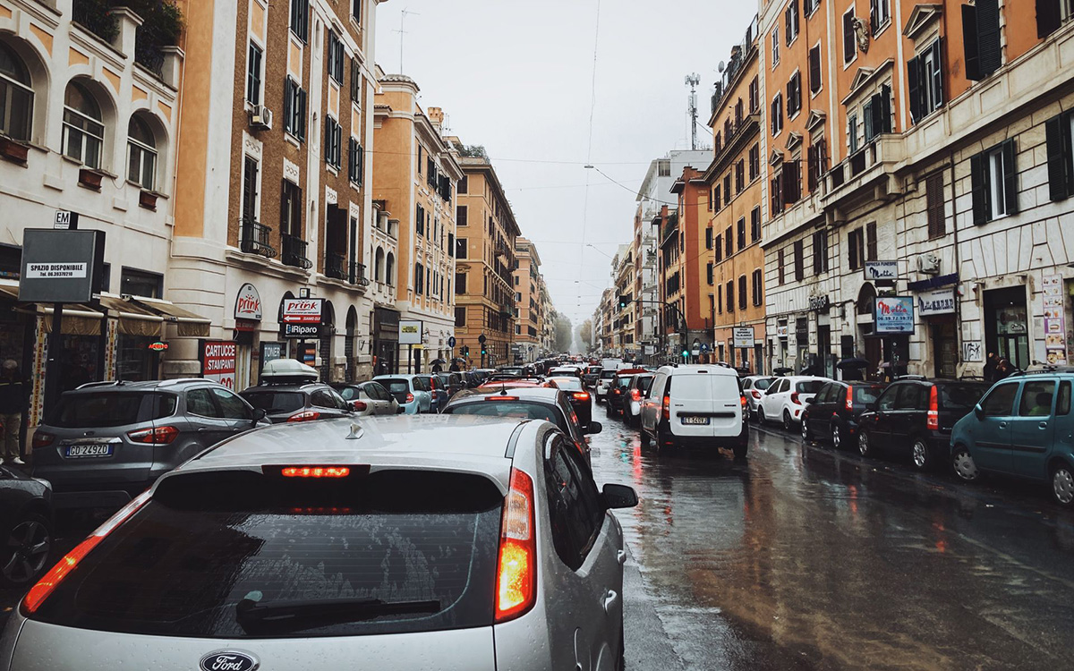 Heavy traffic on a rainy day in central Rome with cars driving through a busy city street.