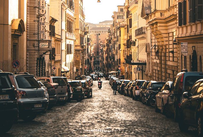Parking in Rome on a narrow cobblestone street lined with parked cars in the historic city centre.