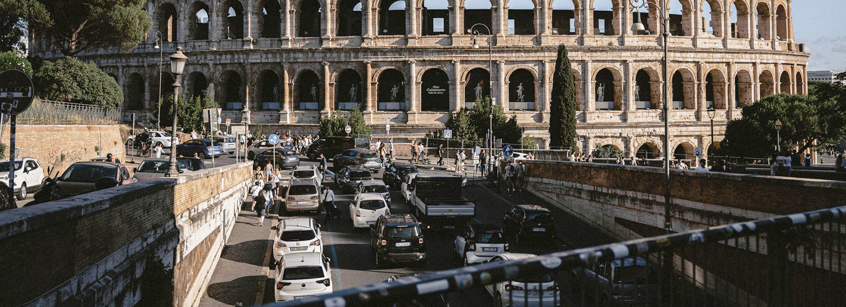 Wide view of traffic around the Colosseum with busy roads and Rome's historic city centre.
