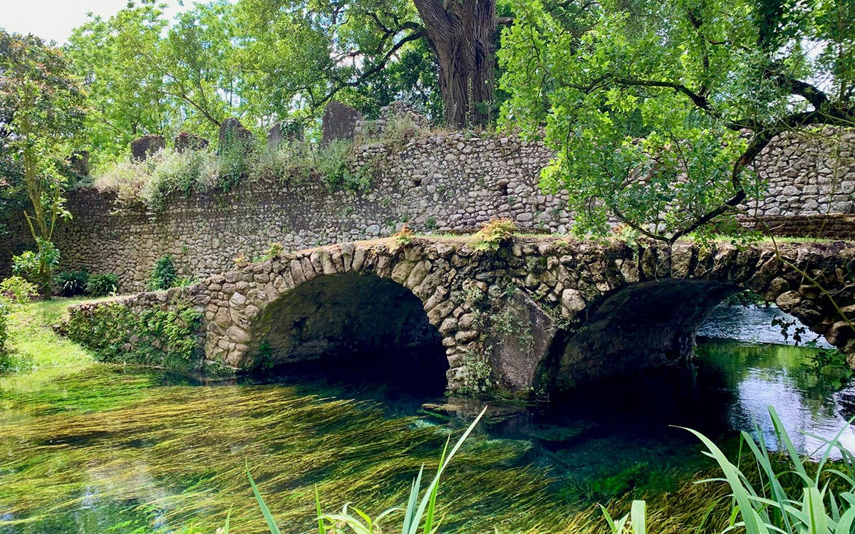Arched bridge and green banks along the Ninfa river