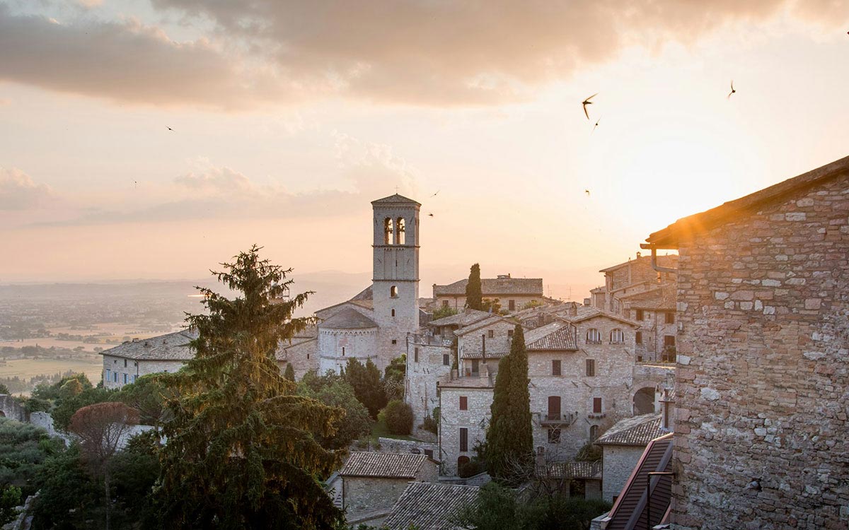 Assisi old town and bell tower glowing at sunset over Umbria