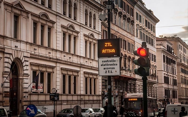 Red ZTL attiva sign above a camera notice on a street in Rome warning drivers that the limited traffic zone is active